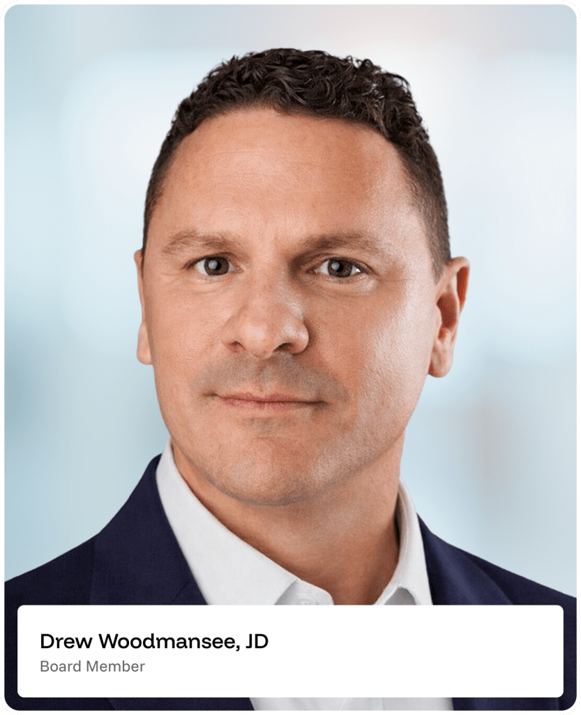 Professional headshot of a man with short curly brown hair, wearing a dark jacket and white shirt, against a blurred light blue background. Text below reads: Drew Woodmansee, JD Board Member..
