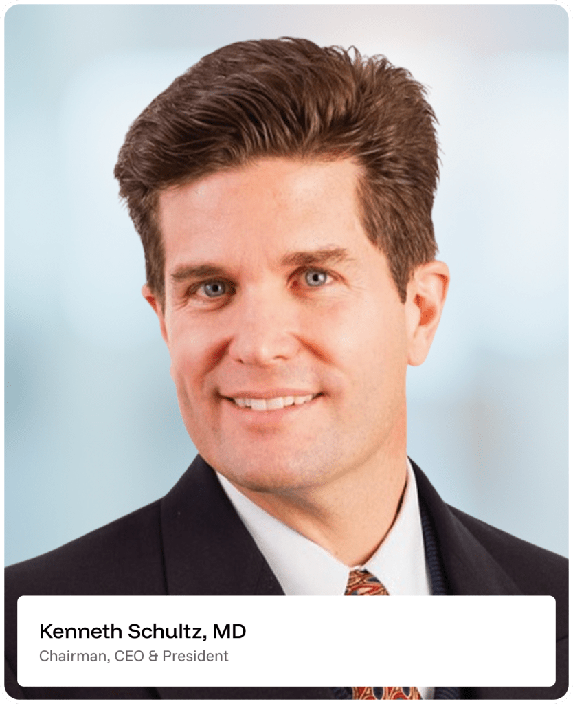 A man in a suit and tie smiles at the camera. Text below reads: Kenneth Schultz, MD, Chairman, CEO & President. The background is softly blurred in blue and white tones.
