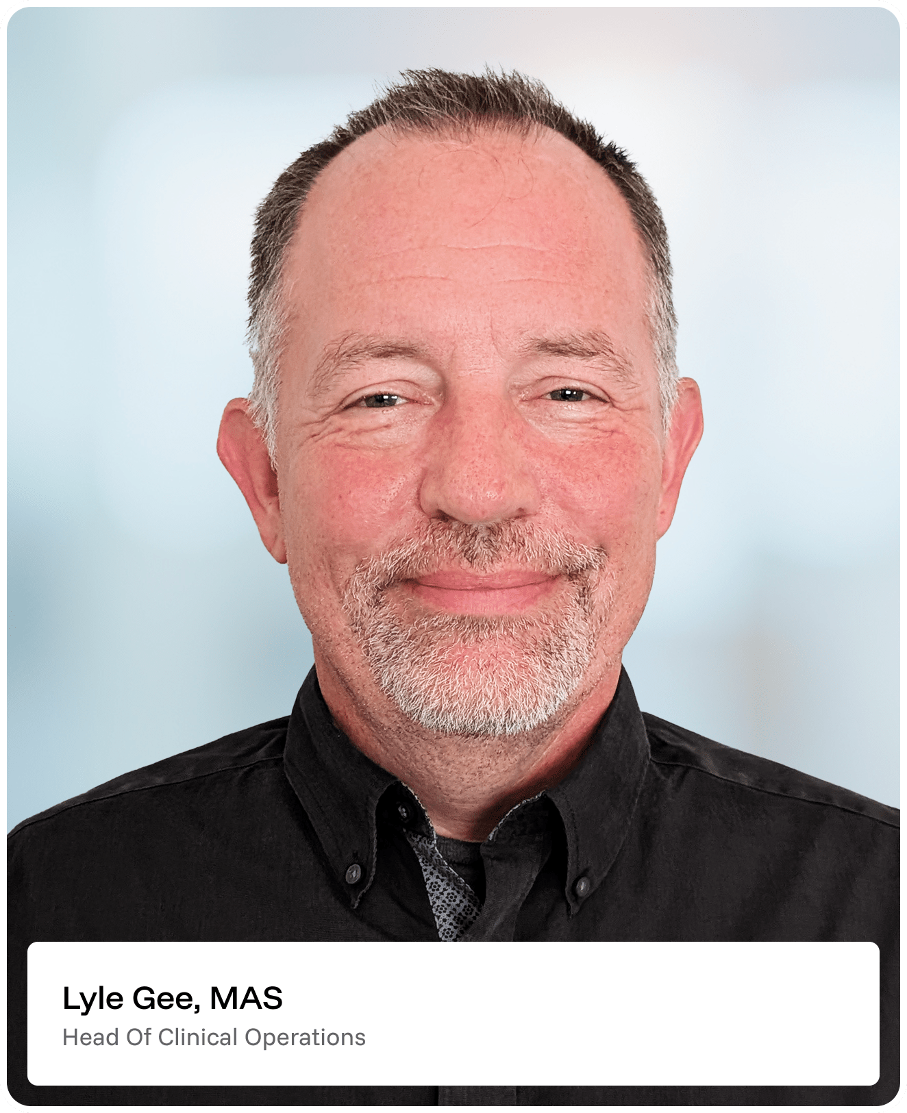 A middle-aged man with short hair, a trimmed gray beard, and a black collared shirt smiles at the camera. Text at the bottom reads, Lyle Gee, MAS, Head of Clinical Operations..