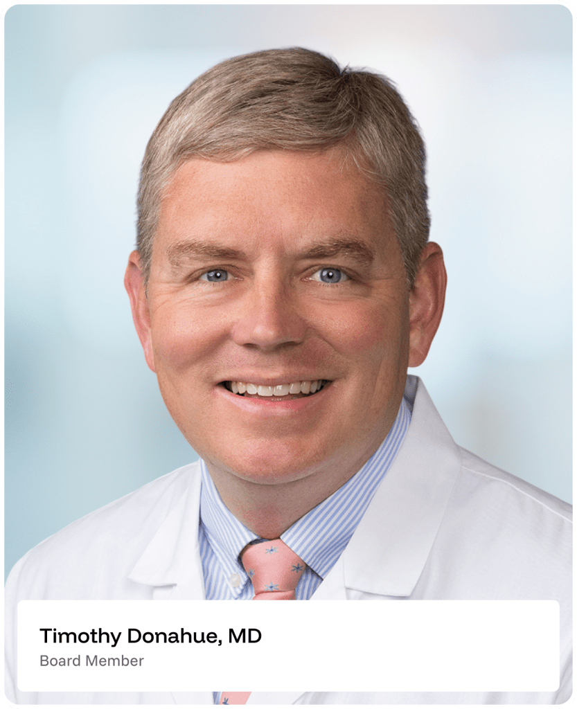 A smiling man in a white medical coat and striped shirt with a pink tie, posing for a professional headshot. A label below reads Timothy Donahue, MD, Board Member..